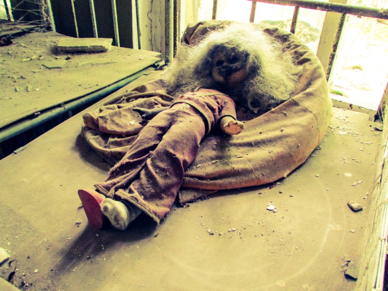 En dukke ligger forlatt på en seng på en av sovesalene.